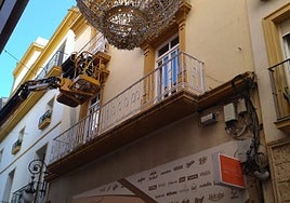 Un operario coloca redes de protección y pinchos en la cornisa de un balcón de la Corredera.