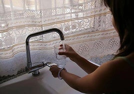 Una mujer echa agua en un vaso.