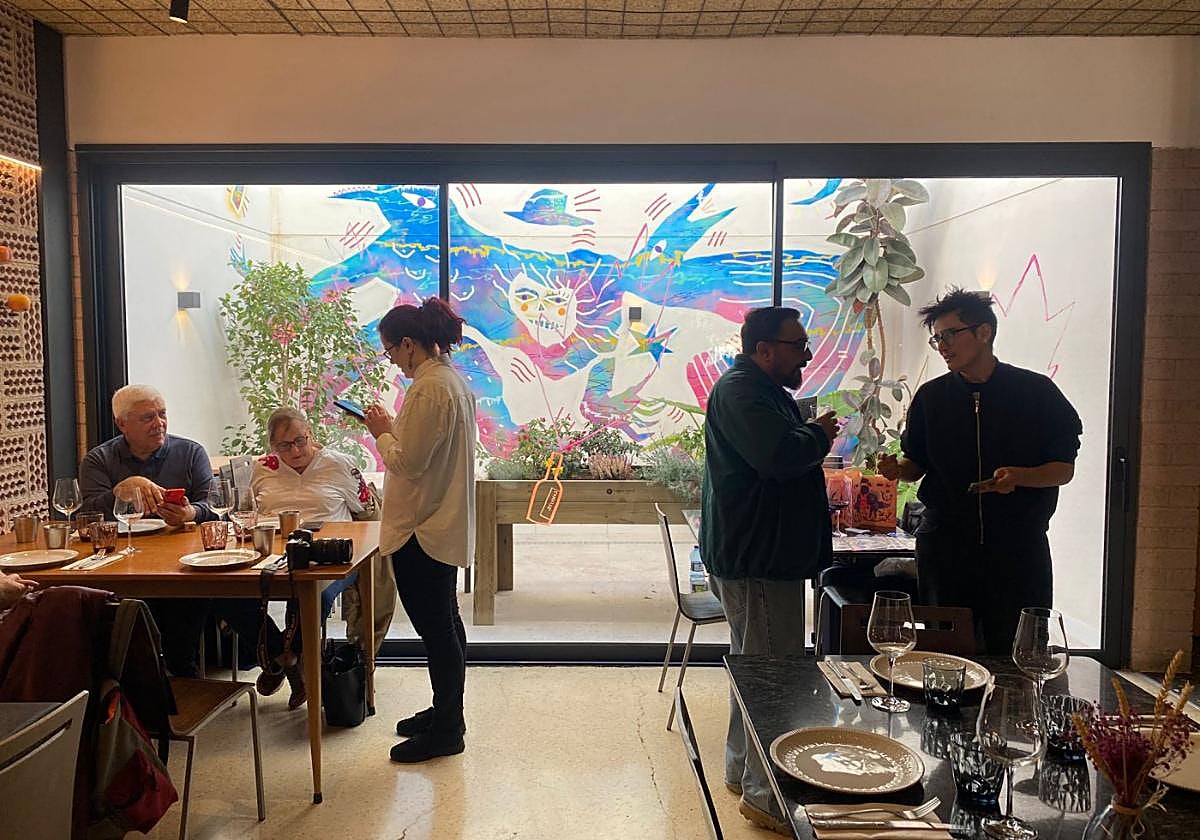 La artista murciana Coco Guzmán, a la derecha; al fondo, la obra en Taller de Sabores.