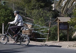 Una ciclista pasa frente al acceso de la Cueva del Agua, precintada tras la muerte de la buceadora.