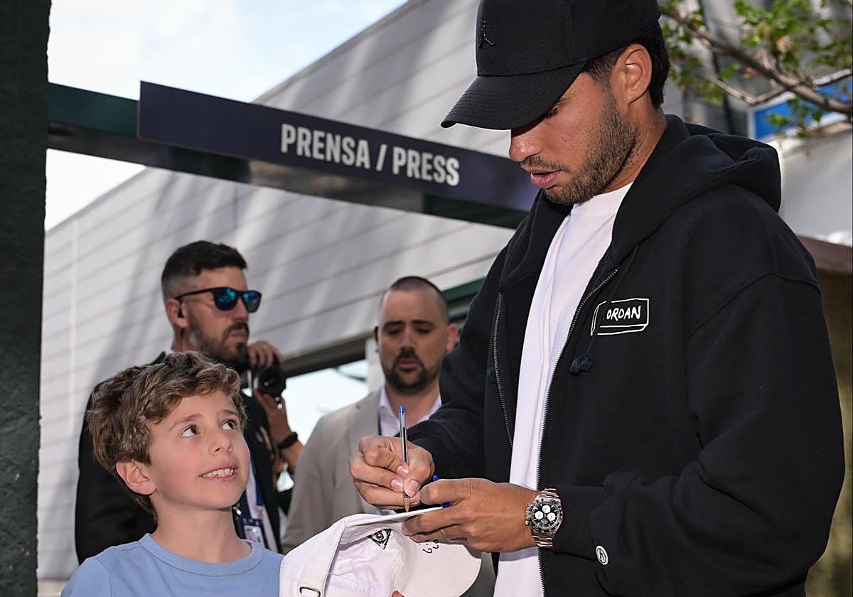 Alcaraz firma una gorra a un pequeño aficionado nada más aterrizar en Barcelona.