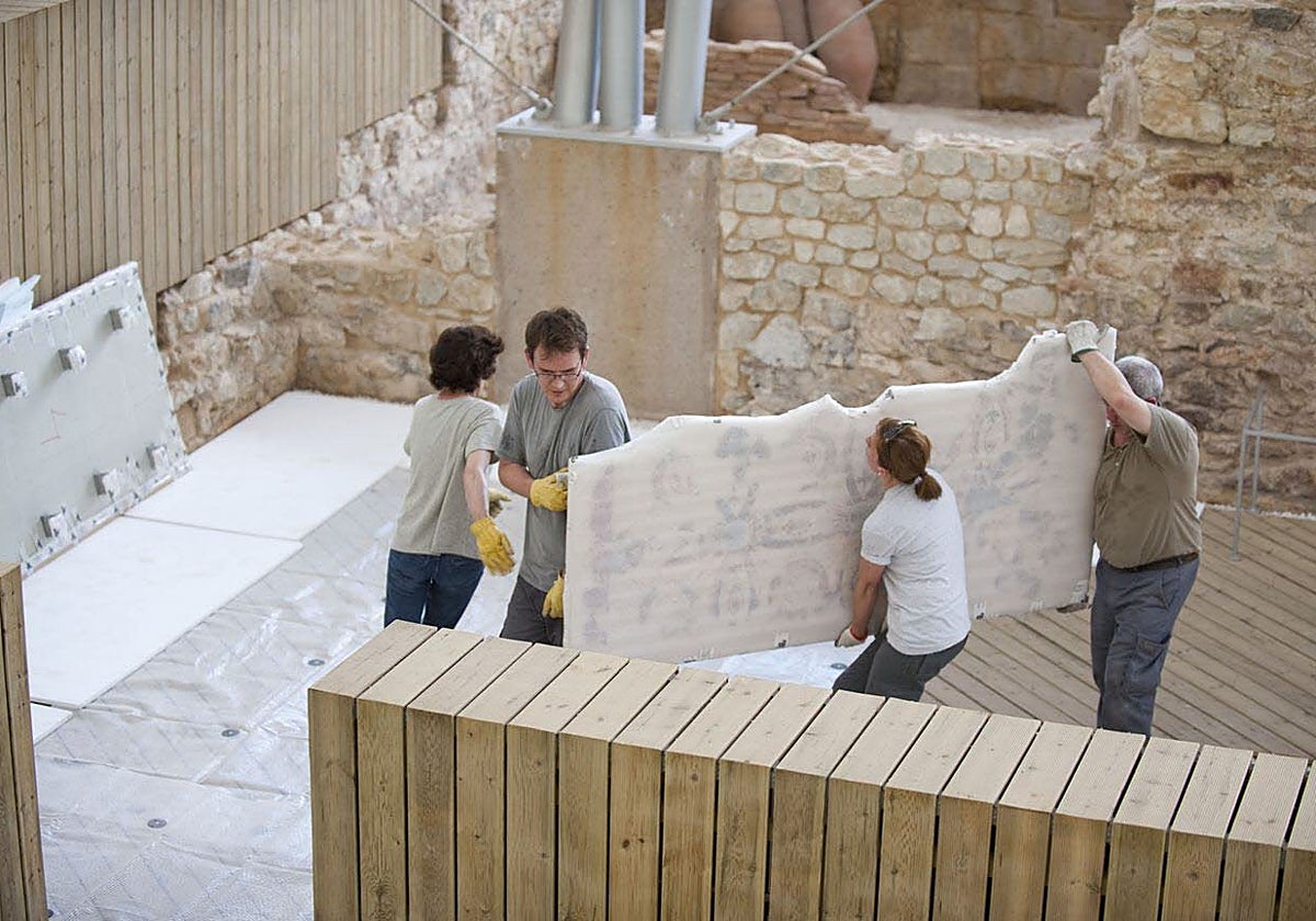 Colocación de las pinturas murales pertenecientes al edificio del atrio del Barrio del Foro Romano del Parque Arqueológico del Molinete tras su restauración por el Instituto de Patrimonio Cultural de España.