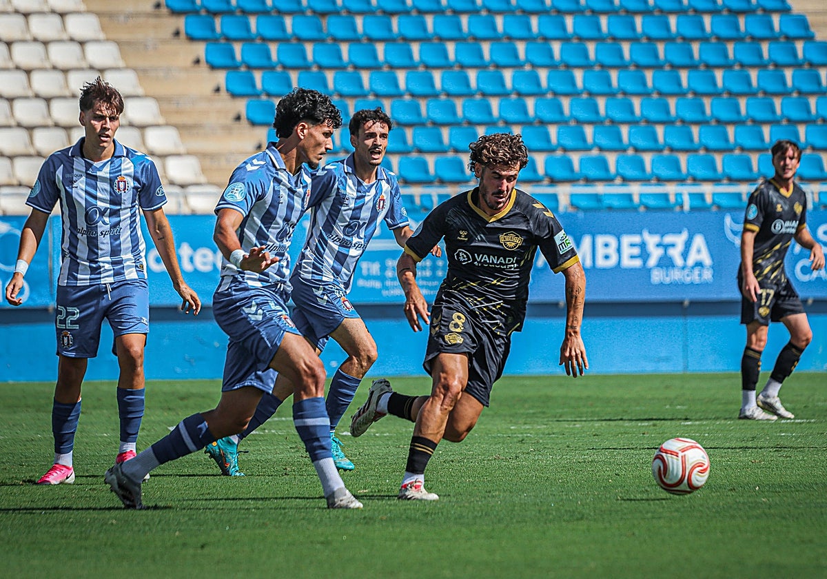 Dani García, del Lorca Deportiva, juega el balón ante la presión de Julio Gracia.