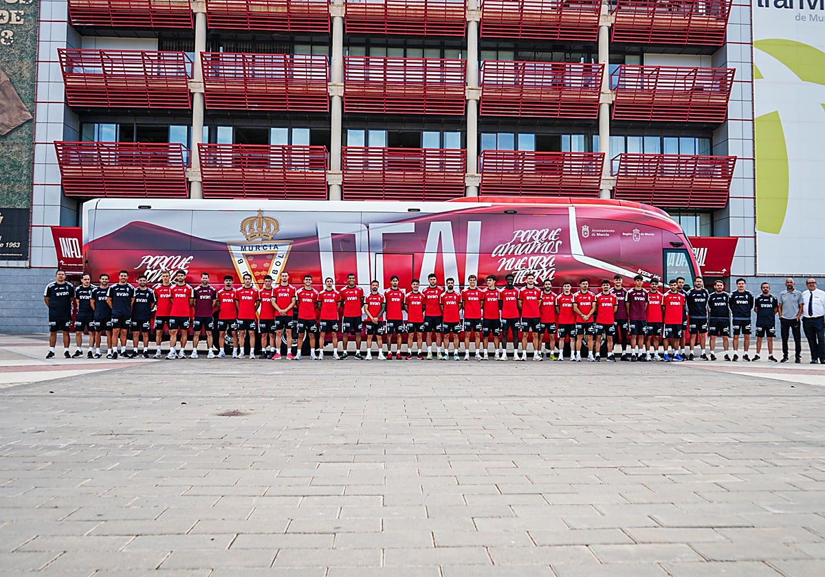 La plantilla y el cuerpo técnico del Real Murcia posan delante del nuevo autobús del equipo.
