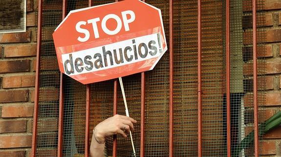 Una mujer sostiene un cartel de 'Stop Desahucios'. 