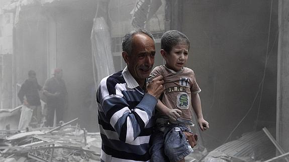 Un hombre sostiene a un niño tras un ataque de las fuerzas del régimen. 