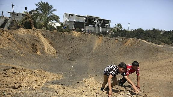 Jóvenes palestinos juegan en el interior de un cráter provocado por un ataque aéreo de aviones israelíes en el este de la ciudad de Gaza. 