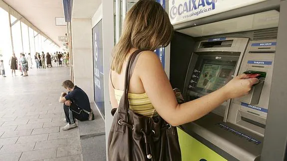 Una joven saca dinero de un cajero automático. 