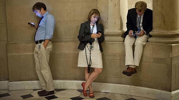 Varios periodistas de EE UU miran sus móviles.