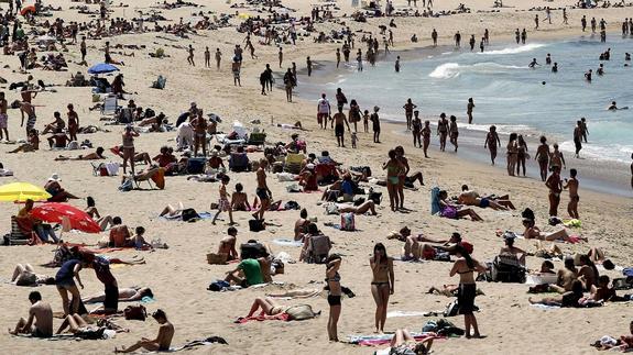 Cientos de personas disfrutan de un día soleado en la playa de La Zurriola de San Sebastián. 