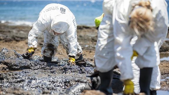 Voluntarios recogen fuel en la playa 'Muelle viejo' de Gran Canaria.