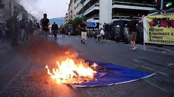 Varias personas protestan contra la UE queman una bandera.