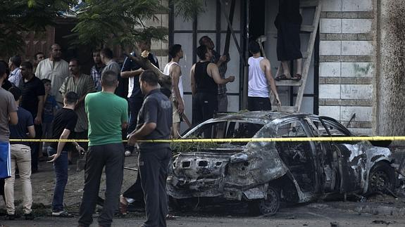 Varios gazatíes alrededor de una de los vehículos calcinados por las explosiones.