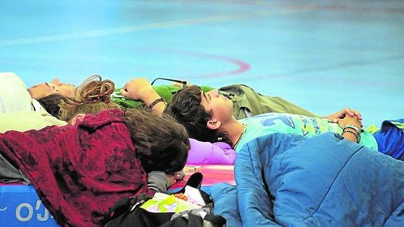 Pasajeros del autobús descansan en el polideportivo del municipio de La Madeleine