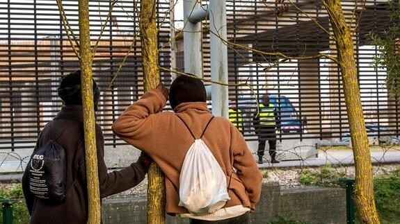 Dos inmigrantes observan a los agentes del Eurotunnel. 