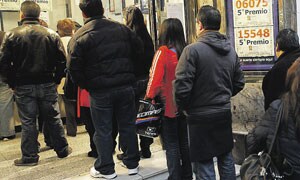 Varias personas guardan cola en una céntrica administración madrileña para comprar sus décimos de Lotería del Niño. EFE
