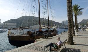 EN EL MUELLE. Un hombre, en un banco del Alfonso XII, frente a la goleta. / ANTONIO GIL / AGM
