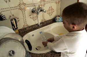 PARA BEBER. Un niño llena una botella de agua en el grifo de su casa. / SONIA M. LARIO. / AGM