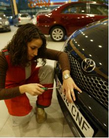 DE ESTRENO. La empleada de un concesionario coloca la matrícula a un coche. La foto es de archivo. / NURIA GONZÁLEZ