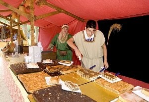 Un comerciante parte unos trozos de tarta para mostrarlos al público. /JOSÉ ALBALADEJO / AGM