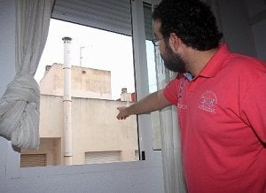 Daniel Pando señala desde su habitación la salida de humos de la panadería. ::                             PABLO SÁNCHEZ/ AGM