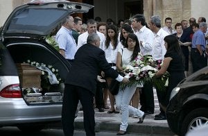 Dos jóvenes depositan ramos de flores en el coche fúnebre que trasladó los restos de Marta Acosta. ::                             JOSÉ MARÍA ROGRÍGUEZ/AGM