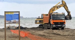 Un camión y una máquina excavadora retiran las piedras y la tierra de uno de los espigones de la playa de Los Urrutias. ::                             ANTONIO GIL / AGM