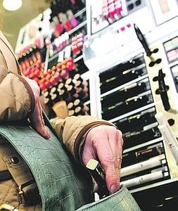 Una mujer mete en su bolso un producto de maquillaje. ::                             EDU BOTELLA / AGM