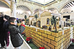 Un niño hace una fotografía a la maqueta del belén municipal, que ha vuelto al patio porticado del Palacio de Guevara, ayer. :: Paco Alonso/AGM