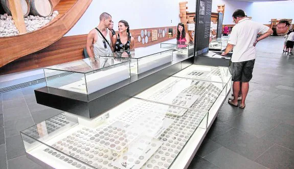 Varios visitantes observan las vitrinas con las monedas de oro y plata del tesoro clasificadas, en el Arqua. :: j. m. rodríguez / agm
