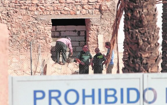 Dos guardias civiles inspeccionan el monasterio, mientras un trabajador tabica una ventana. 