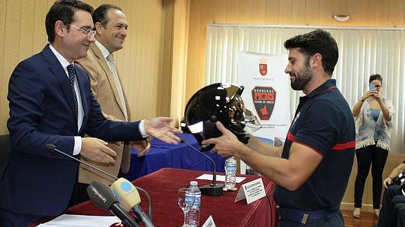 El consejero de Empleo entrega su casco a uno de los nuevos bomberos del Consorcio. 