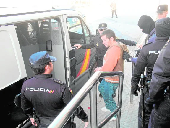 Arriba, uno de los detenidos, al ser conducido a un furgón por agentes de la Policía Nacional en Los Mateos.