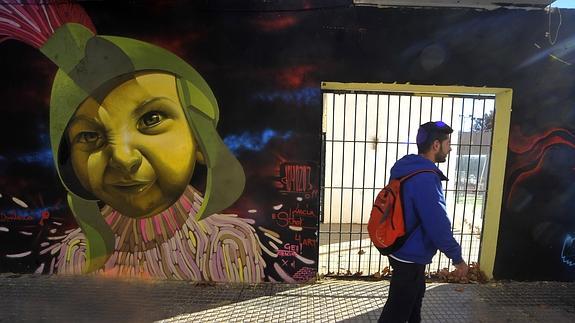 Un joven pasa por delante de uno de los grafitis pintados sobre los muros de la Casa de la Juventud.