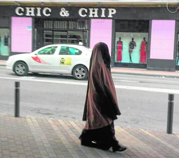 Una mujer con burka pasea por la calle García Alix. 