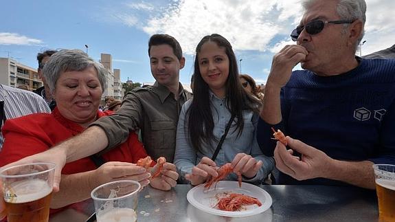 Un grupo de asistentes disfrutan de un plato de gambas.