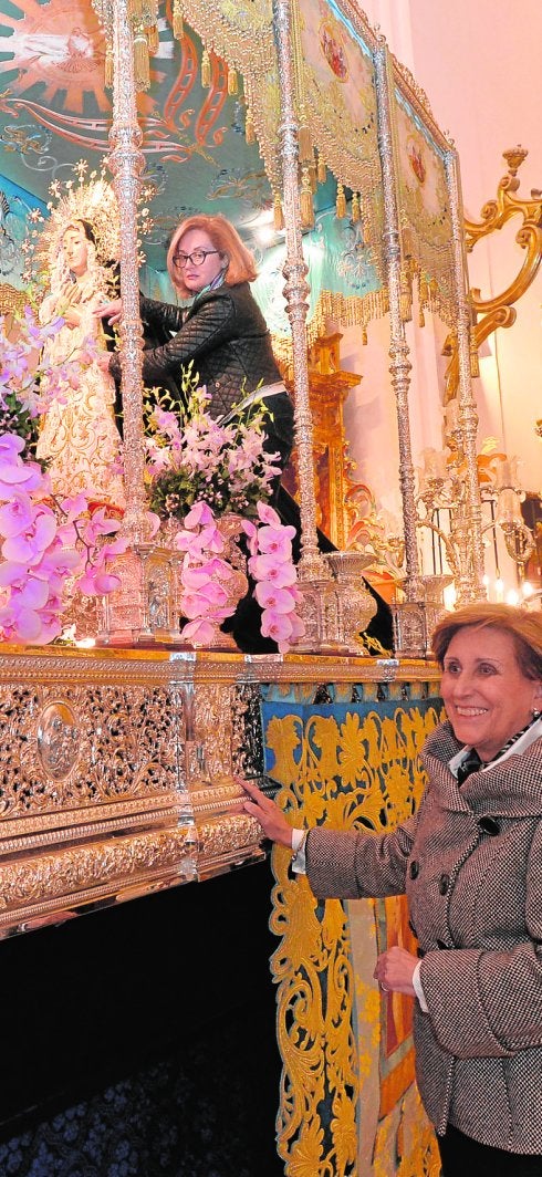 Una azul retoca el manto negro de la Dolorosa instantes antes de iniciarse la Septena en presencia de la Camarera de la Virgen.
