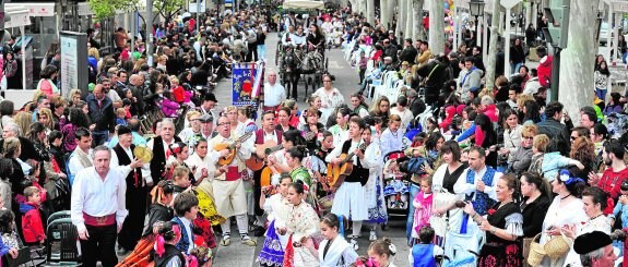 Panorámica de la avenida Alfonso X El Sabio, abarrotada de gente, mientras un grupo de coros y danzas interpreta jotas. 