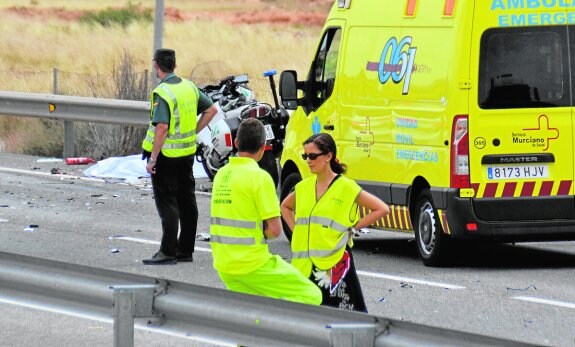 Agentes de Tráfico y de conservación de carreteras trabajan en el lugar del accidente. 