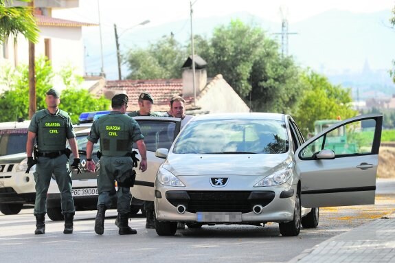 Agentes de la Guardia Civil introducen en el coche a uno de los detenidos tras el registro. 