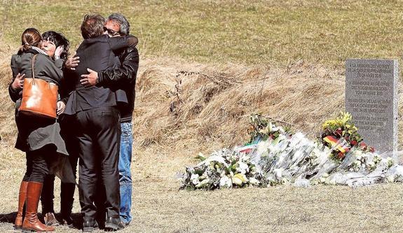 Familiares de Francisco Javier Moreno se abrazan junto a una lápida que recuerda el accidente. 