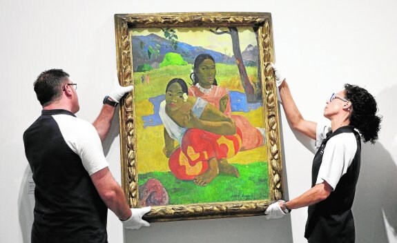 Dos operarios del Reina Sofía colgando ayer en la planta cuarta del museo '¿Cuándo te casarás?', pintado por Paul Gauguin en 1892. :: Reuters
