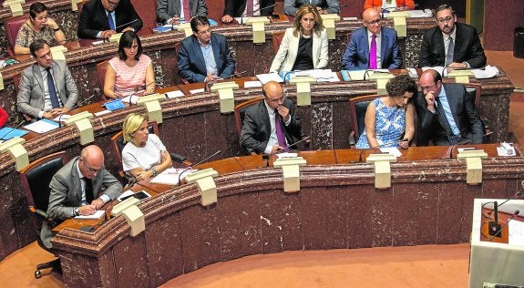 Sánchez intercambia impresiones con su consejera de Presidencia, María Dolores Pagán, durante el Pleno. 