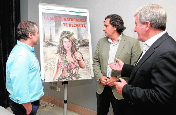 El pintor Miguel Vivo muestra el cartel de la campaña 'Camino del Sol' al presidente de Anpier, el murciano Miguel Ángel Martínez-Aroca, y al presidente de Fecoam, Santiago Martínez. 