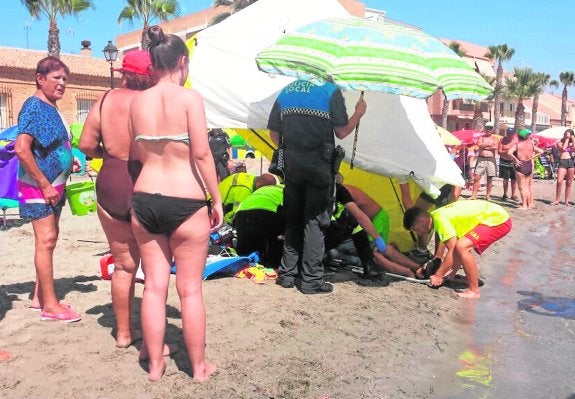 Miembros de los servicios de Emergencias atienden al hombre sobre la arena. 