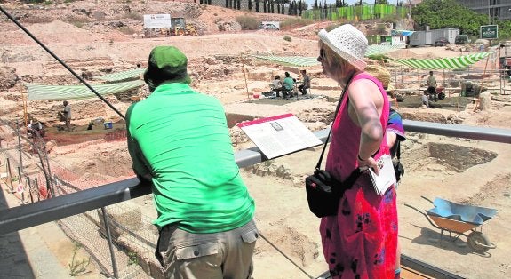 Dos turistas contemplan el trabajo de los arqueólogos en el Barrio del Foro Romano.