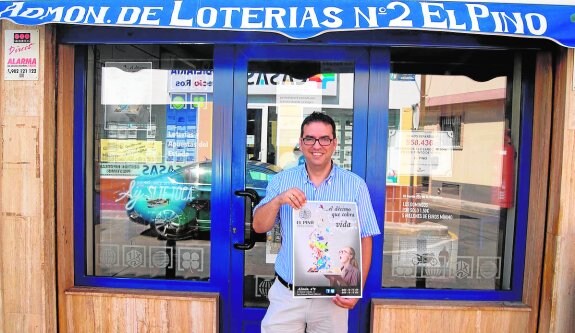 Miguel Ángel Zapata, con un cartel del nuevo décimo, en la puerta de su establecimiento. 