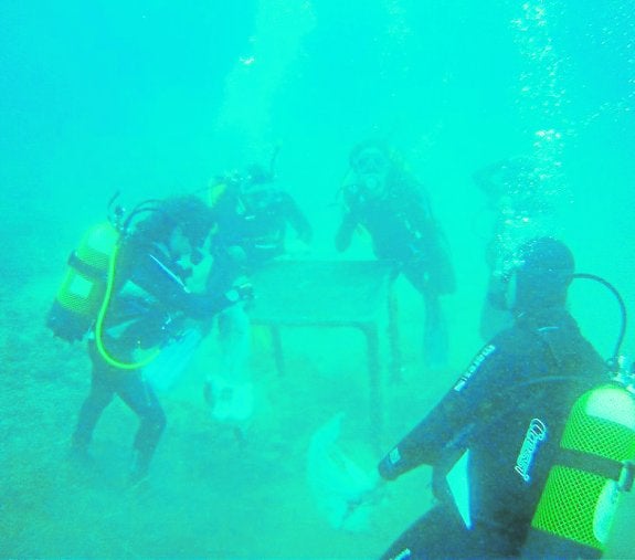 Buceadores voluntarios retirando una mesa del fondo del mar.