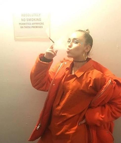 Miley Cyrus de naranja con su cigarro de hierba en la mano.