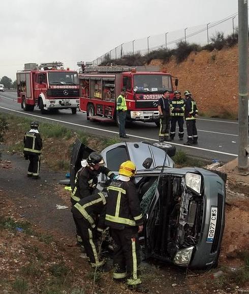 Varios bomberos rescatan a los ocupantes del vehículo que quedaron atrapados. 